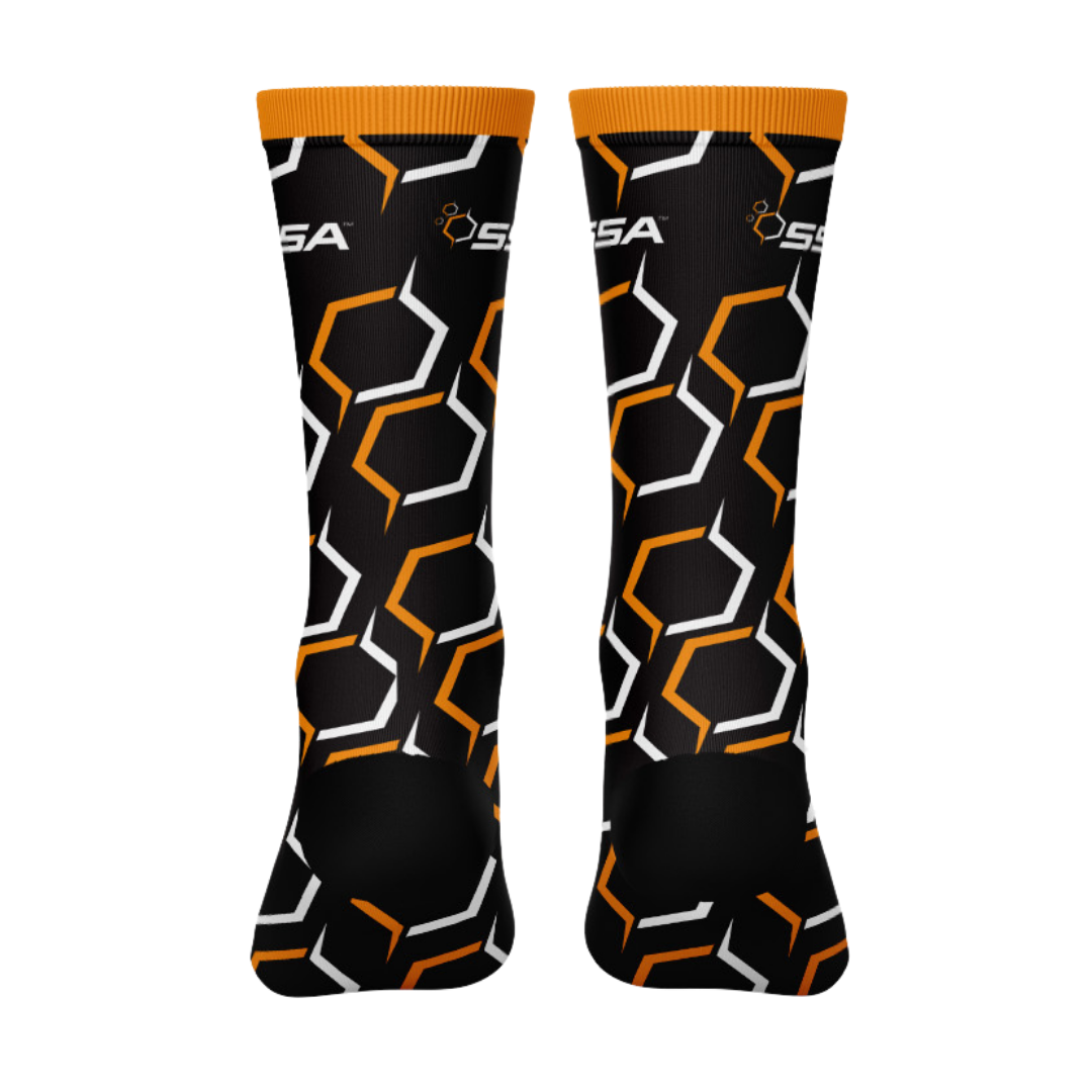 A pair of black crew cut socks with orange and white geometric pattern, featuring the SSA logo.